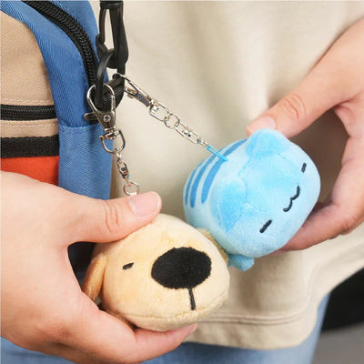 Close-up of Dogdog Lazy Plush Charm and Capoo Lazy Plush Charm clipped to a bag, both being held by hand.